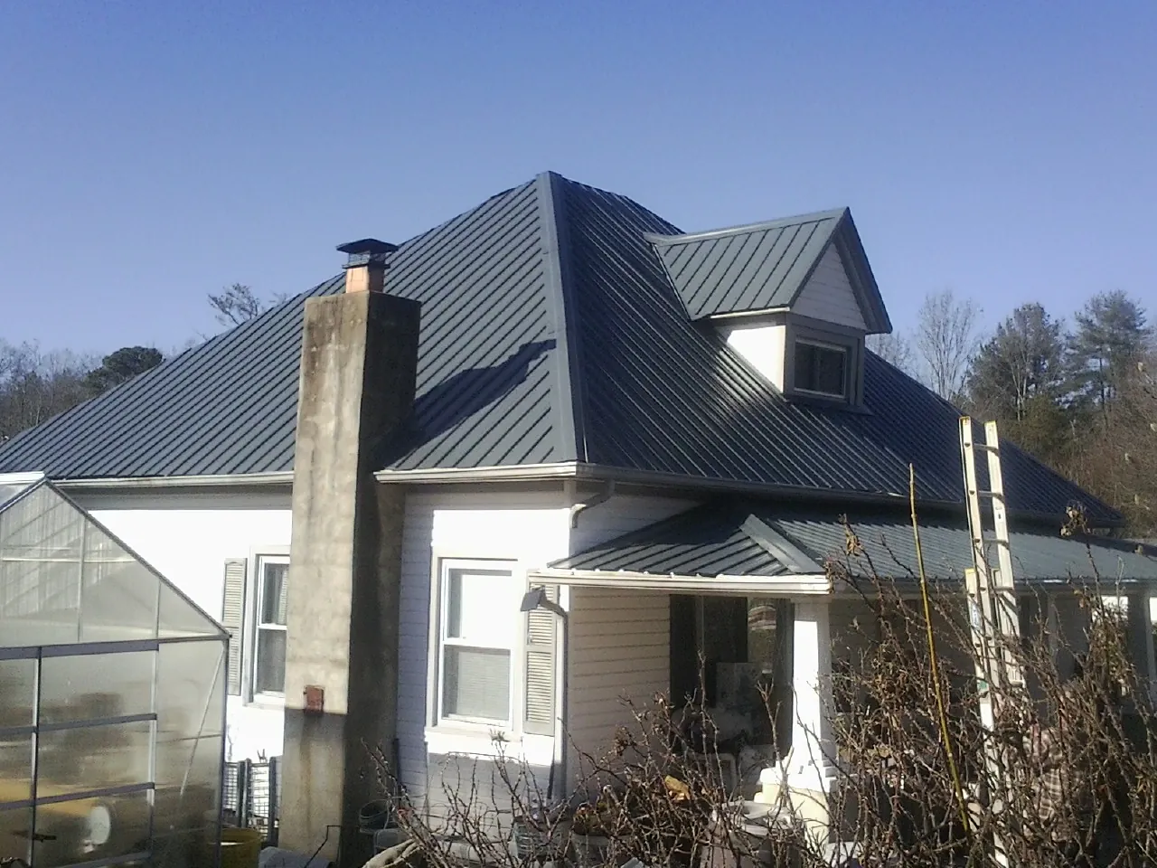 Dark blue standing seam metal roof on a white farmhouse with dormer — Slate & Tile Roof Repair by Roofing Brothers in Westbrook