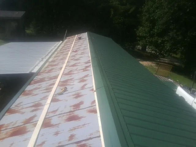 Old rusted panels beside newly installed green metal roofing — Wind Damage Roof Repair by Roofing Brothers in Westbrook