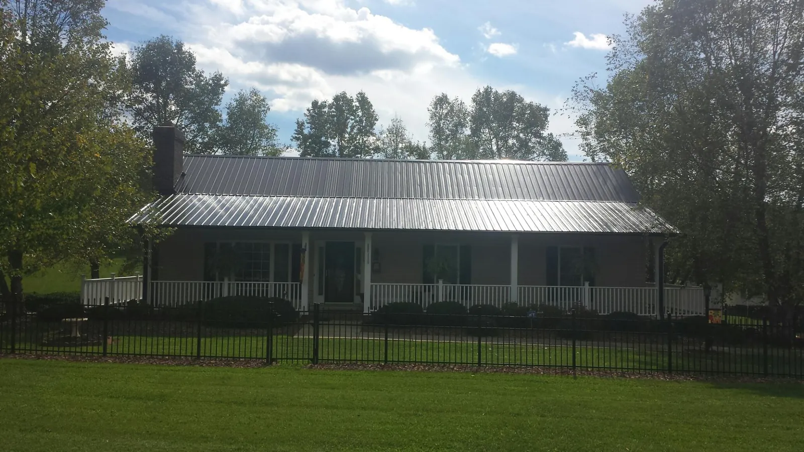Gray metal roof on a brick ranch with a full width front porch — Gutter Guard Installation work by our crew in Westbrook
