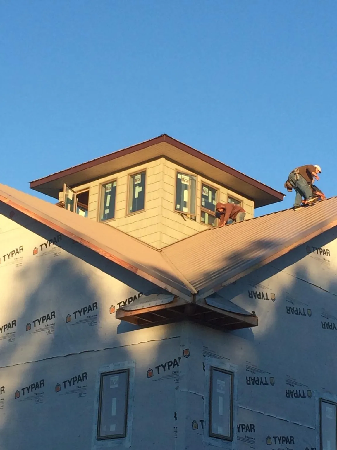 Roofers working around a rooftop cupola on a new metal roof at sunset — Roof Waterproofing in Westbrook by Roofing Brothers